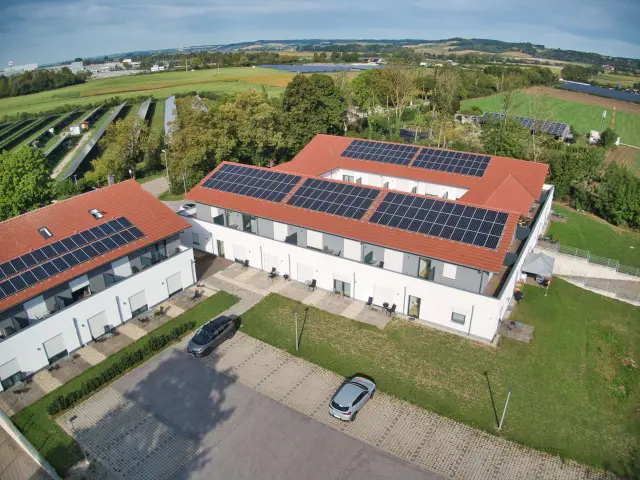 Luftaufnahme des Apartmenthauses Dingolfing mit Parkplätzen und Photovoltaikanlage